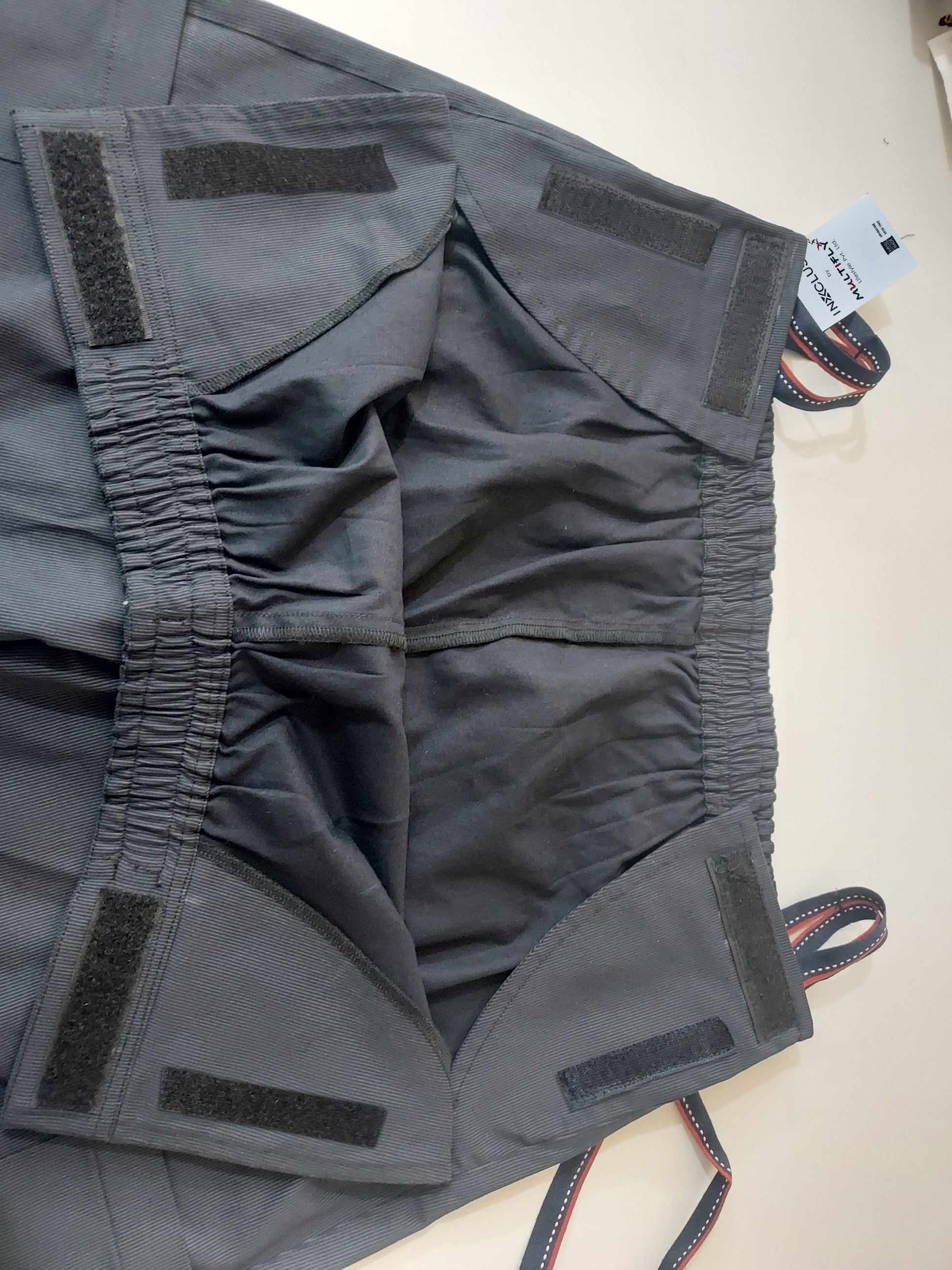 In this picture, one can see the front of the trousers opened fully. elastic, loops and velcros are visible.